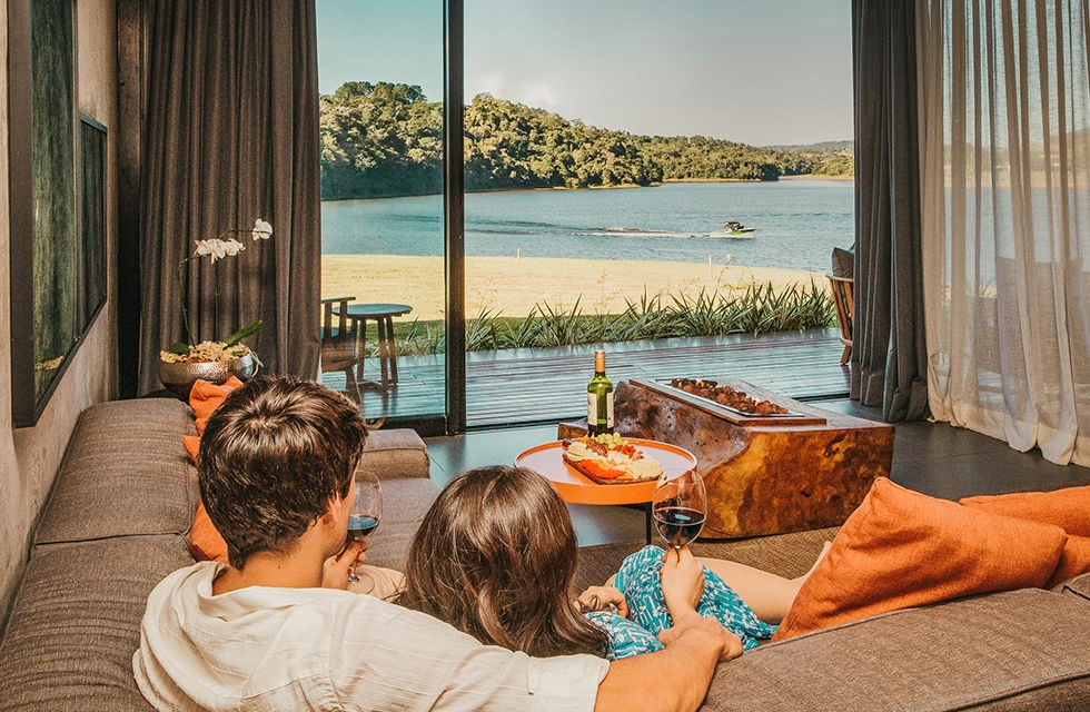 casal tomando vinho e apreciando a paisagem do quarto do clara ibiuna